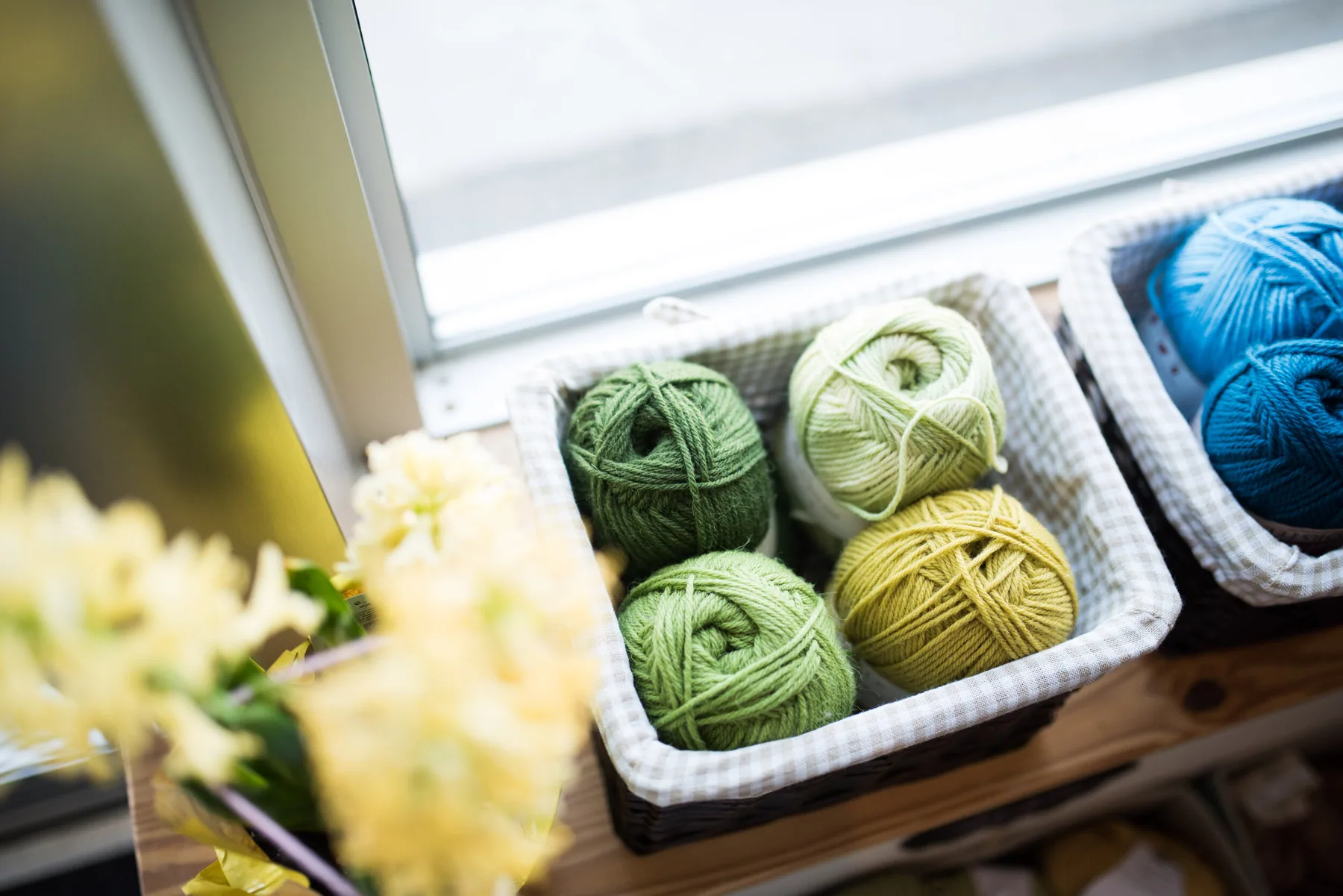 Green, yellow and blue yarn balls arranged in baskets